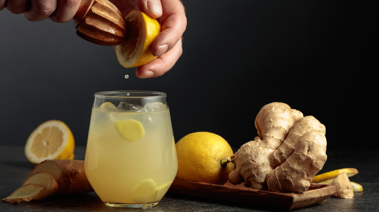 Glass of ginger ale, with a person juicing a lemon into it