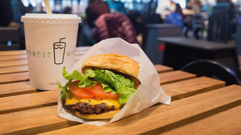 a Shake Shack burger on a table next to a milkshake.