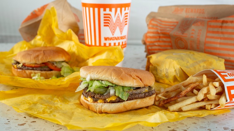 an assortment of burgers from Whataburger complete with fries and a drink.