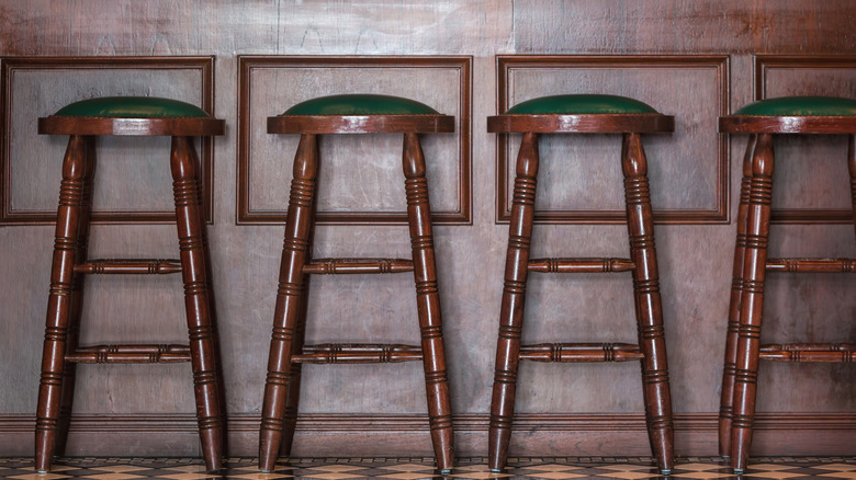 Four vintage bar stools with green leather seats