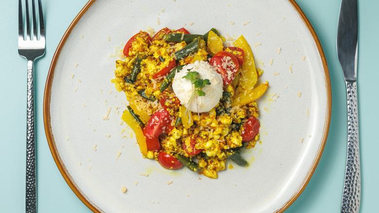 Tofu scramble on a white plate, knife and fork on either side