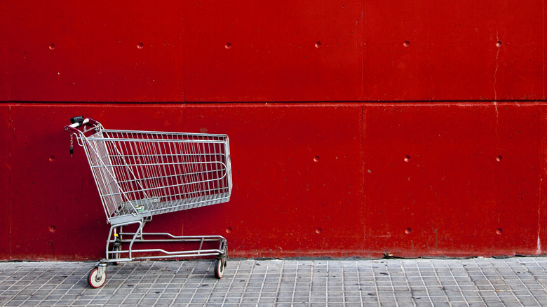 Empty shopping cart against a red wall