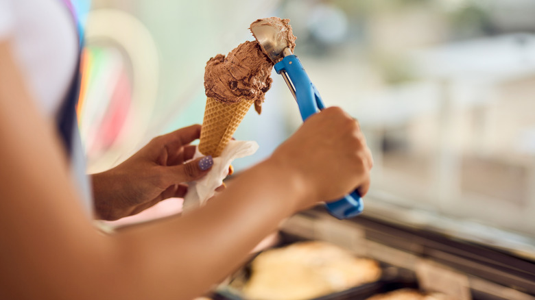 Woman scooping chocolate ice cream into cone