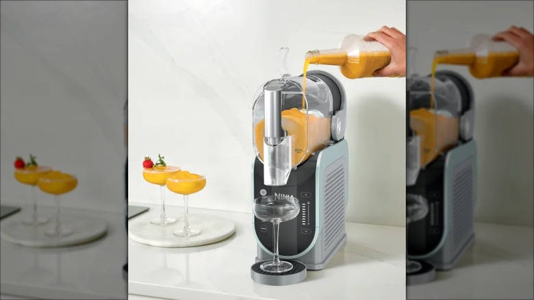 Person making an orange frozen cocktail with the Ninja SLUSHi drink maker