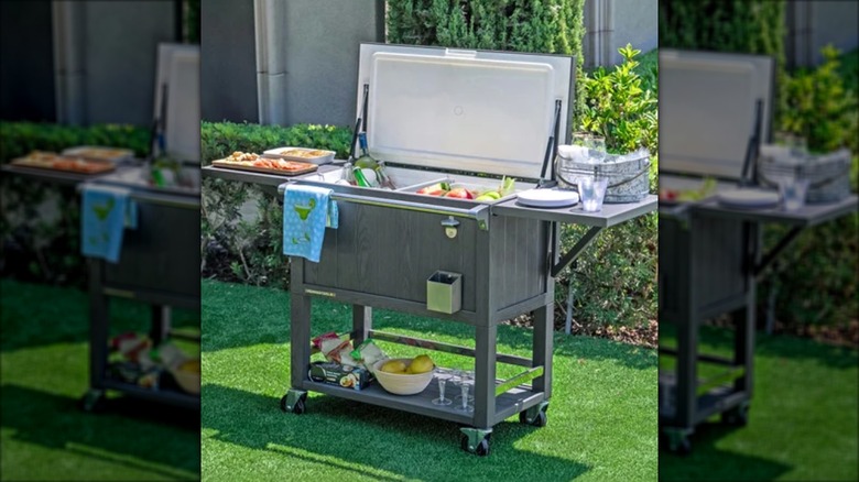 Permasteel beverage cart standing in a garden, loaded with drinks, snacks, and serviceware