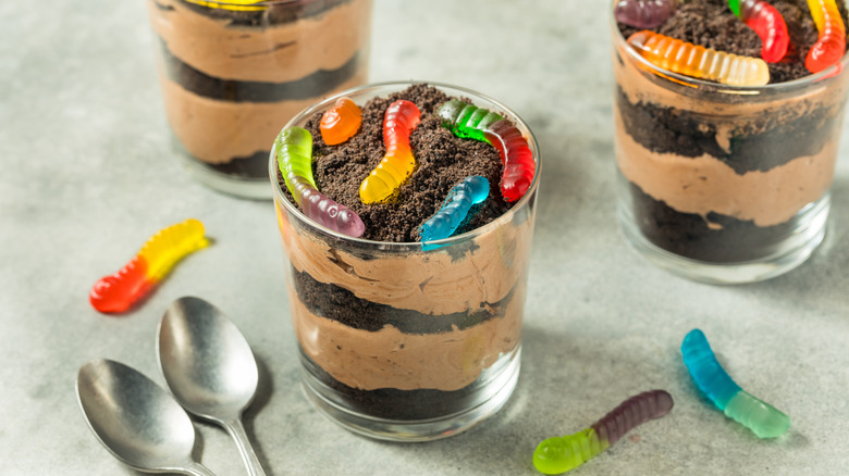 Glass cups of dirt pudding with visible gummy worms poking out of the top.