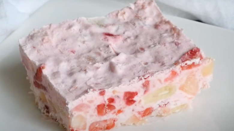 A pink slice of frozen fruit salad with visible strawberries in the middle.