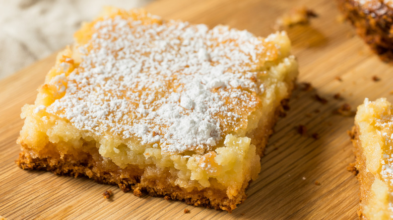 A square of gooey butter cake topped with powdered sugar.