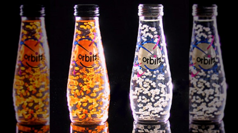 bottles of orange and white orbitz soda glowing against a black background