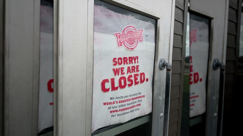 A Fuddruckers restaurant door with a permanent closure sign.