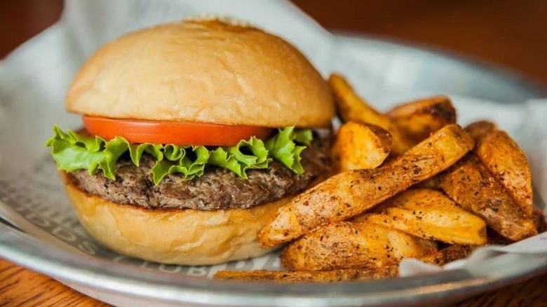 A Fuddruckers burger and fries on a plate.