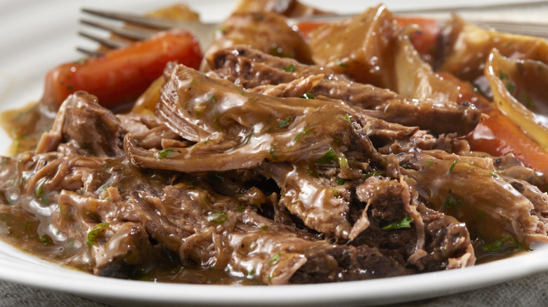 A plate of pot roast with carrots and potatoes