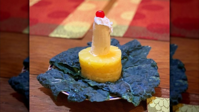 Candle salad with pineapple rings, banana, cream, and a cherry, on a bed of lettuce