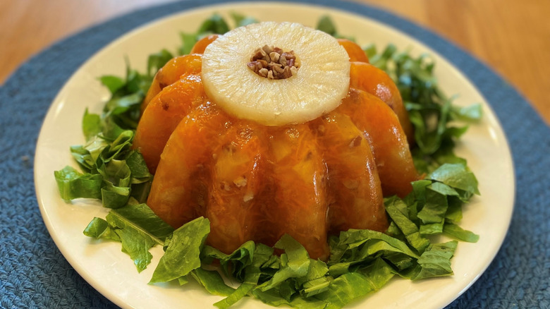 Vintage Jell-O salad on a plate with a bed of lettuce leaves and topped with a pineapple ring