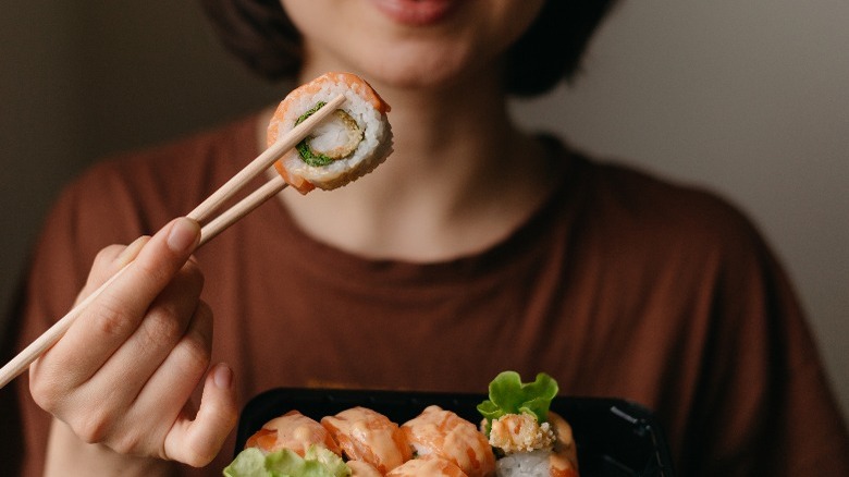 Woman eating sushi with chopsticks