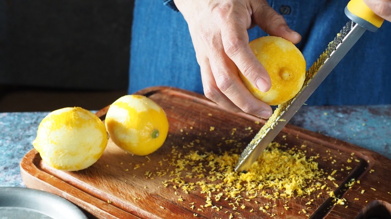 Person zesting three lemons