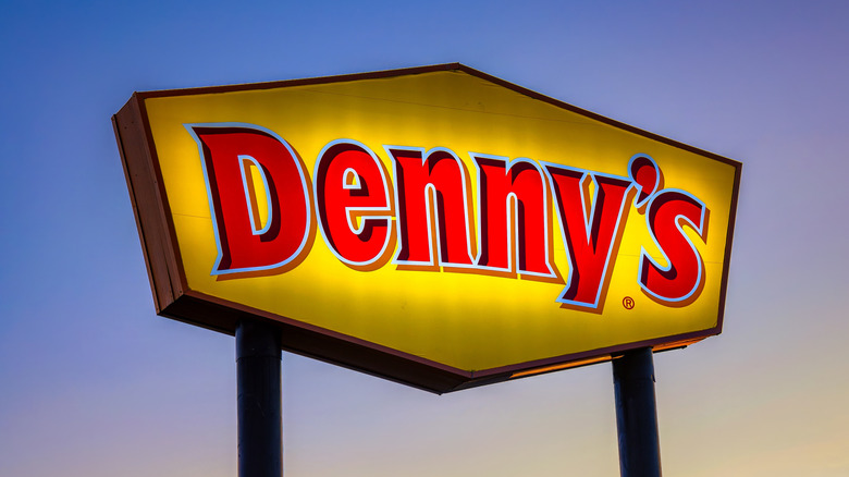 A standalone yellow-and-red Denny's sign at sunrise