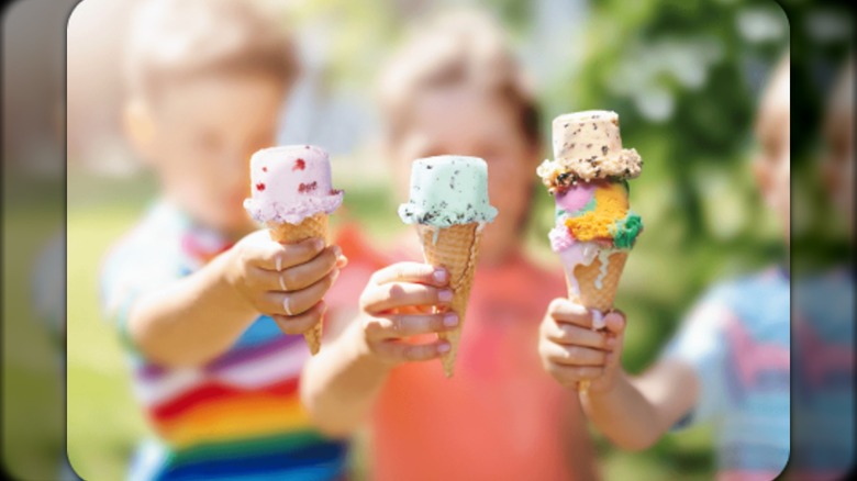 Three kids holding waffle cones with cylindrical, flat-topped scoops of ice cream