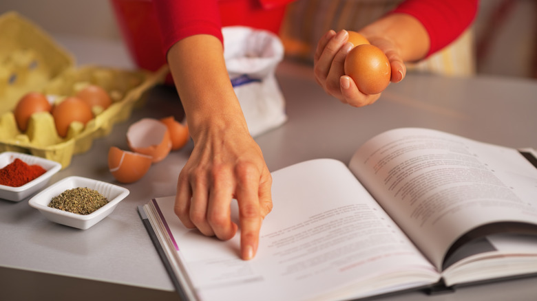 Person reading cookbook while baking