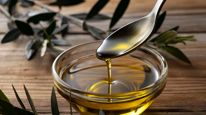spoon drips olive oil into bowl