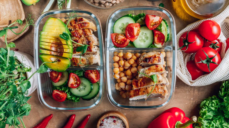 Two meal prep containers on a table of food