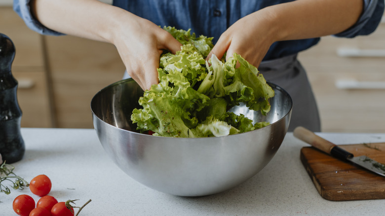 hands tossing salad in bowl