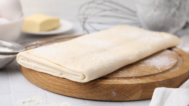 Raw puff pastry dough on a wooden board