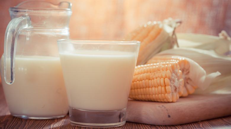 jug and glass of corn milk next to corn on the cobs