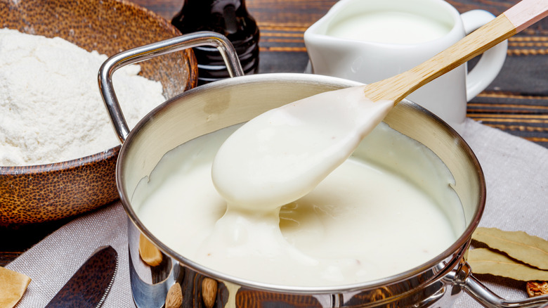 Wooden spoon with a pot of bechamel sauce