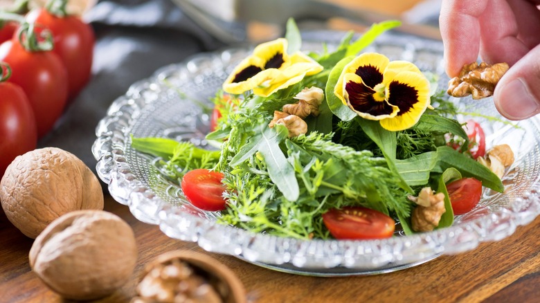 A salad of herbs and edible flowers on glass plate