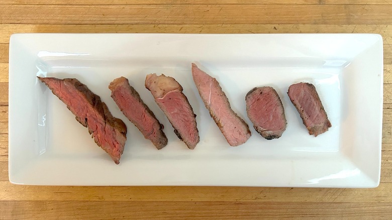 Six pieces of Aldi steak, each from a different cut, lined up on a white plate
