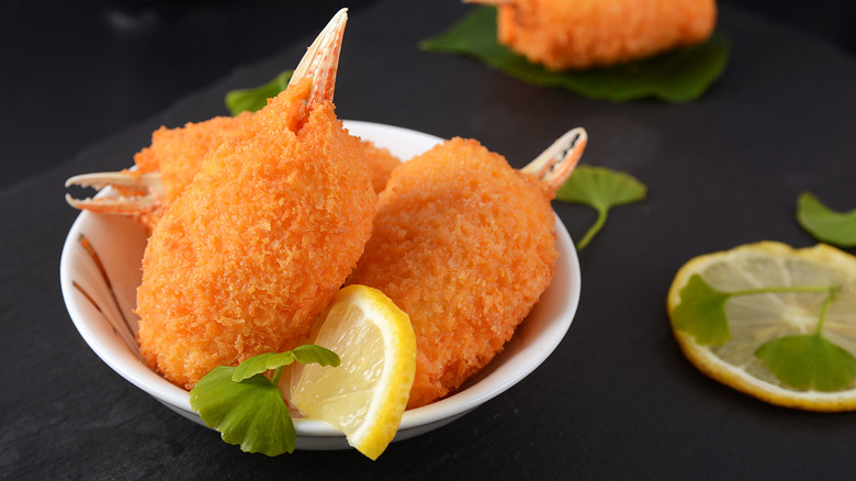 Fried crab claws on a white plate with lemon slices on background