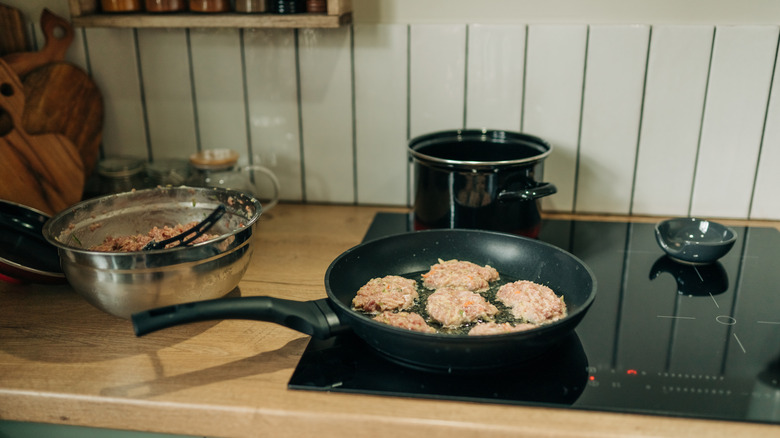 Turkey burgers cooking in a pan on the stove