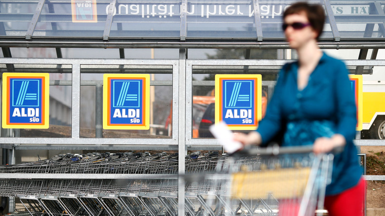 A woman pushing a shopping cart in front of Aldi