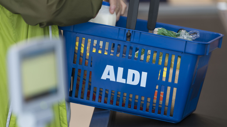 Person holding Aldi basket full of groceries