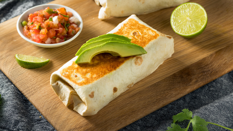burrito with avocado on cutting board