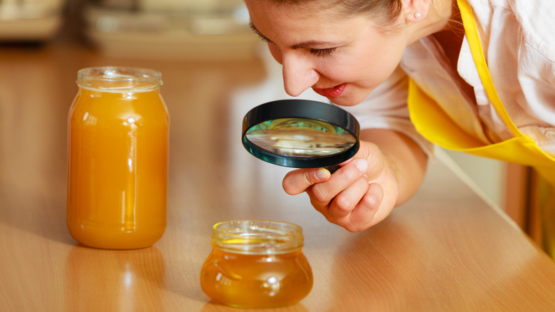 Woman investigating honey with magnifier 