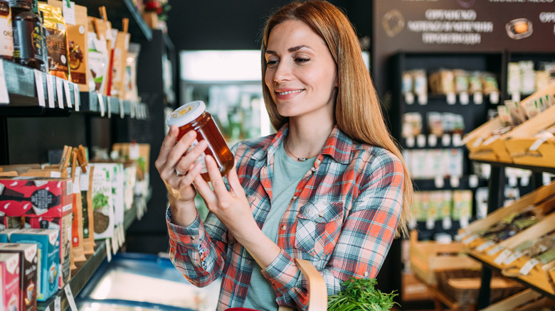 Woman reading label on honey