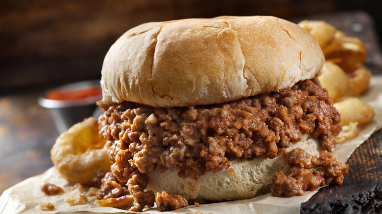 Sloppy Joe sandwich with onion rings in the background