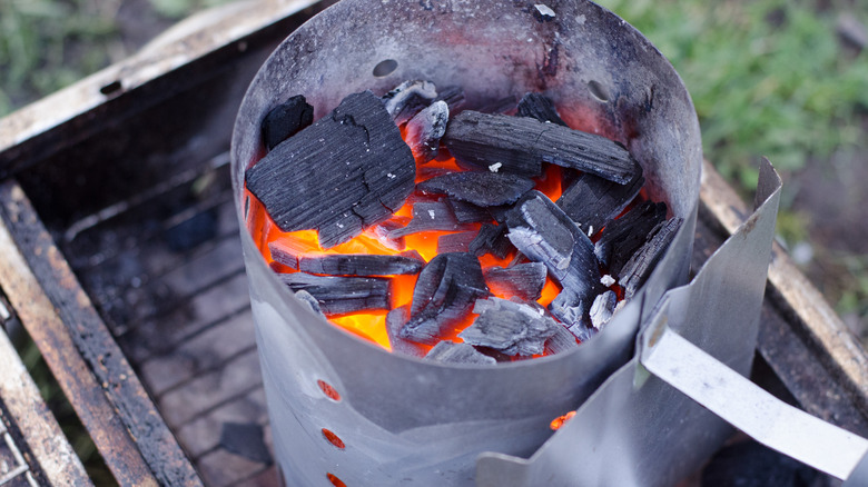 A hot chimney starter on a grill, with red-hot coals and wood burning