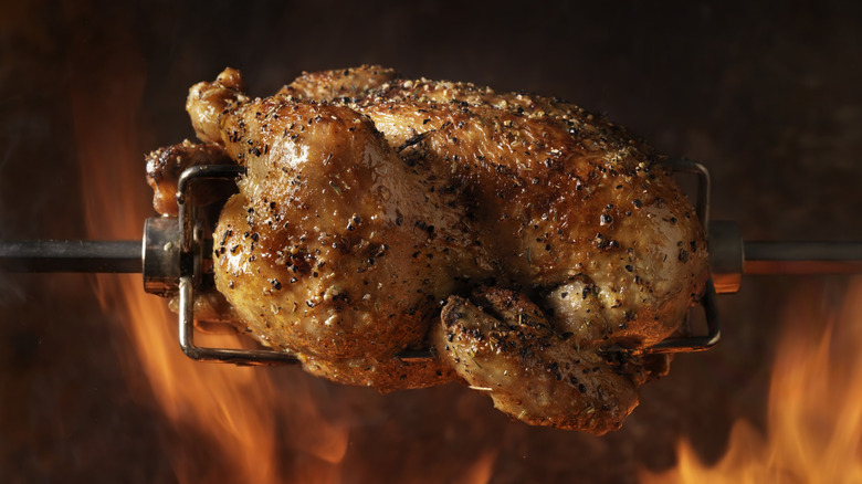 Rotisserie chicken roasting over open flames