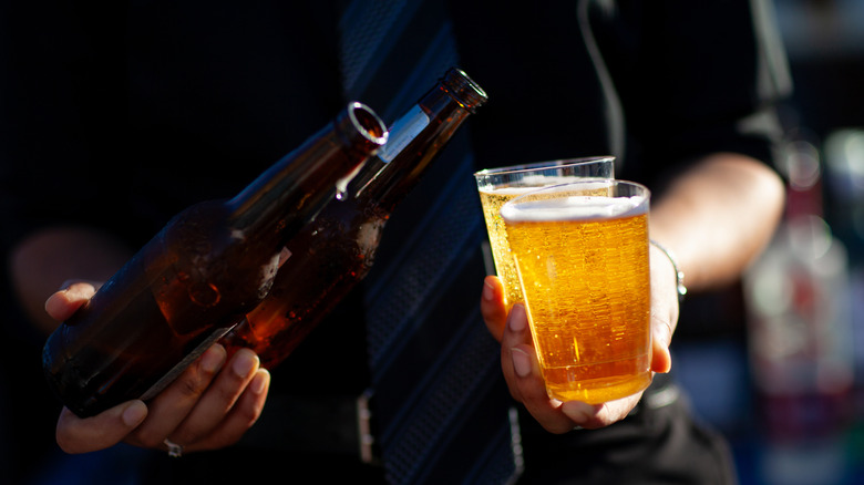 A bartender pouring beer into glasses from bottles