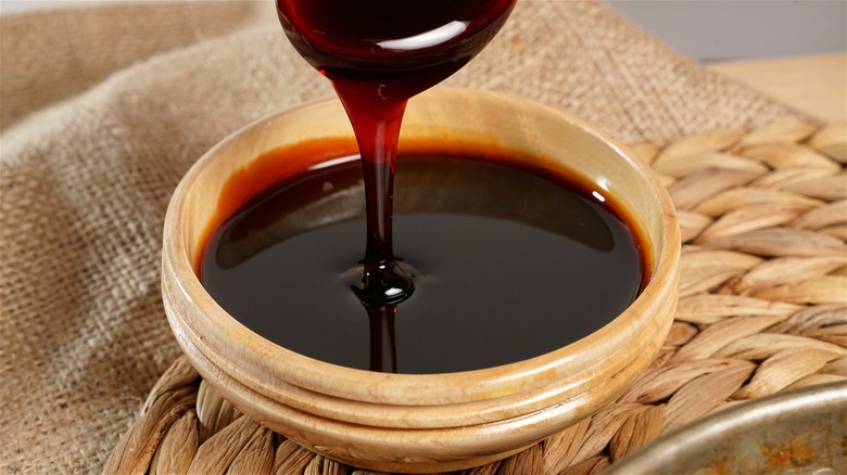 Spooning molasses into wooden bowl 