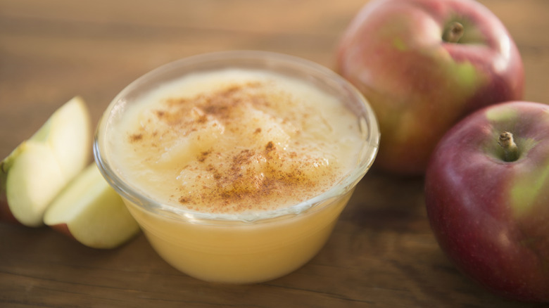 a small glass bowl full of apple sauce surrounded by apples