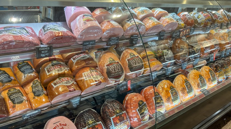 A display case full of unsliced deli meats