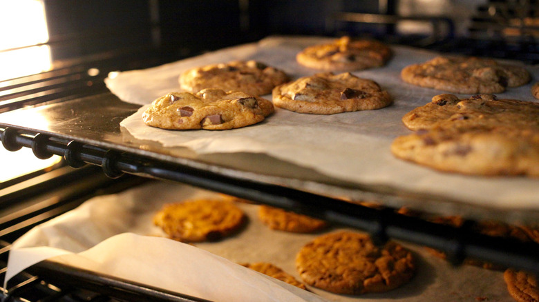 two baking trays of chocolate chip cookies on parchment paper