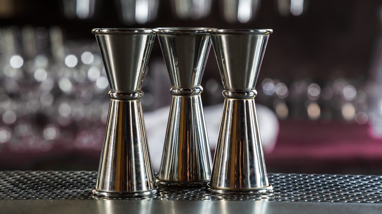 Three cocktail jiggers sitting on bar