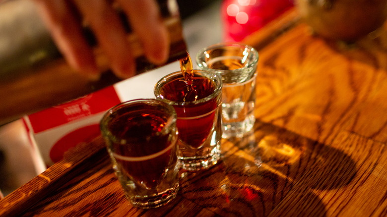 Bartender pouring shots of whiskey into shot glasses
