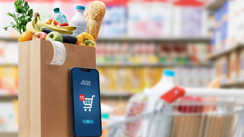 Bag of groceries sitting next to a mobile phone with an online grocery app
