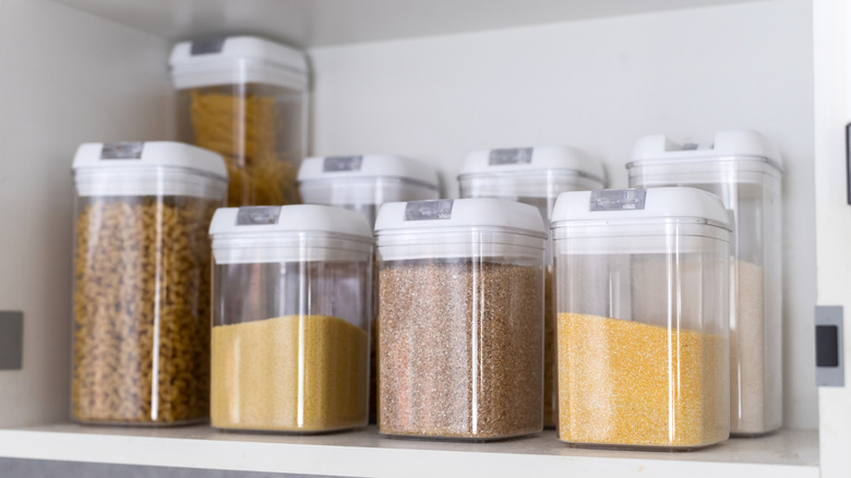 A kitchen shelf lined with square shaped food storage canisters